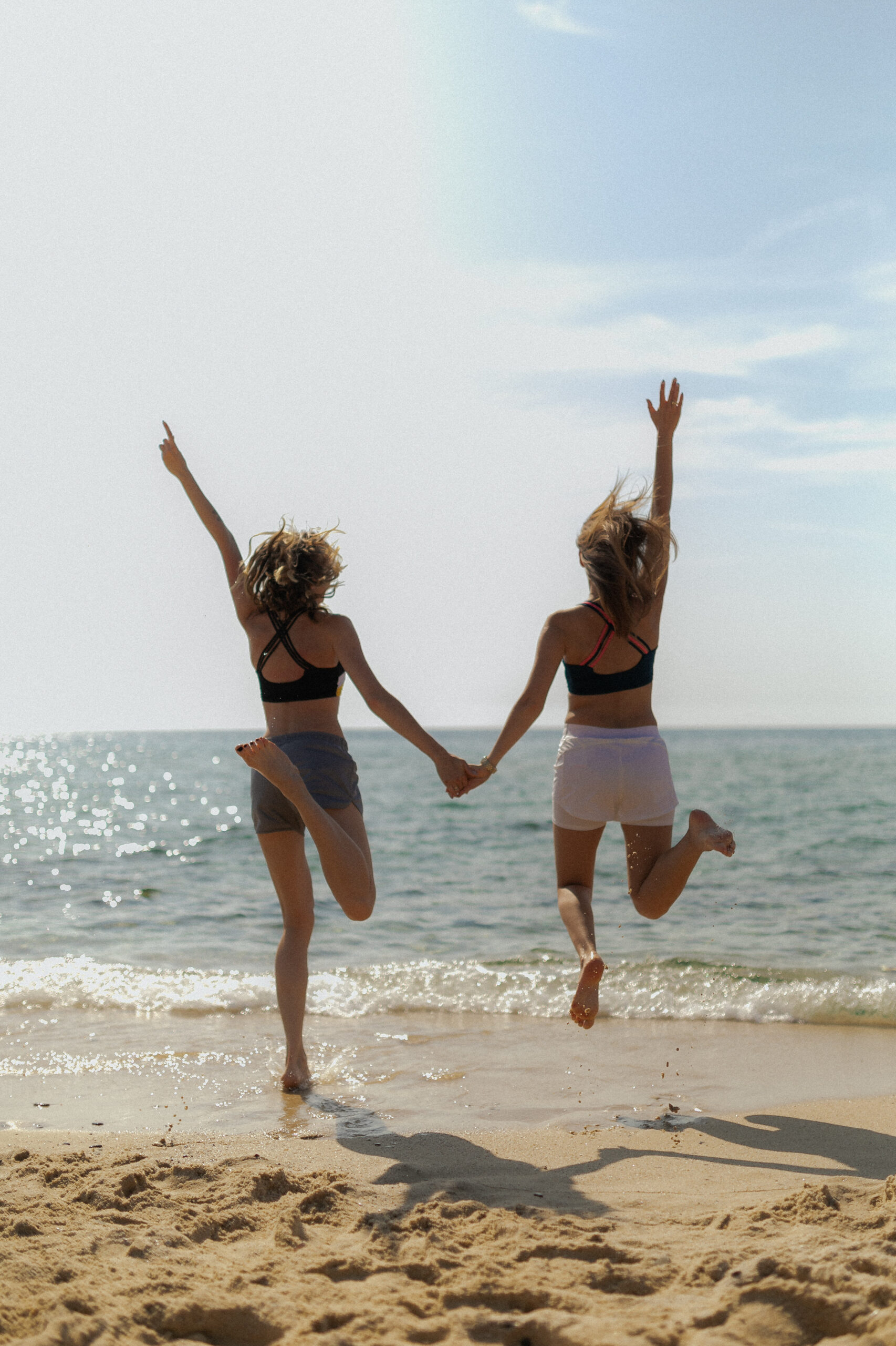 Two stress free girls on the beach celebrating.